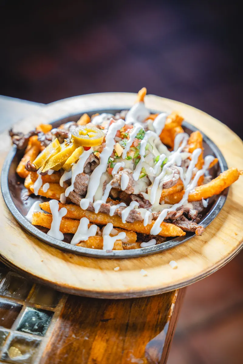 Carne asada fries on a skillet with crema