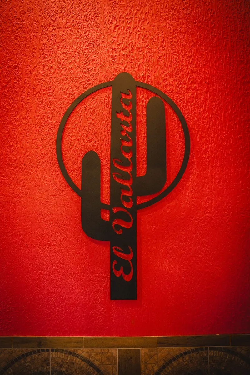 El Vallarta cactus emblem in black metal on a red wall