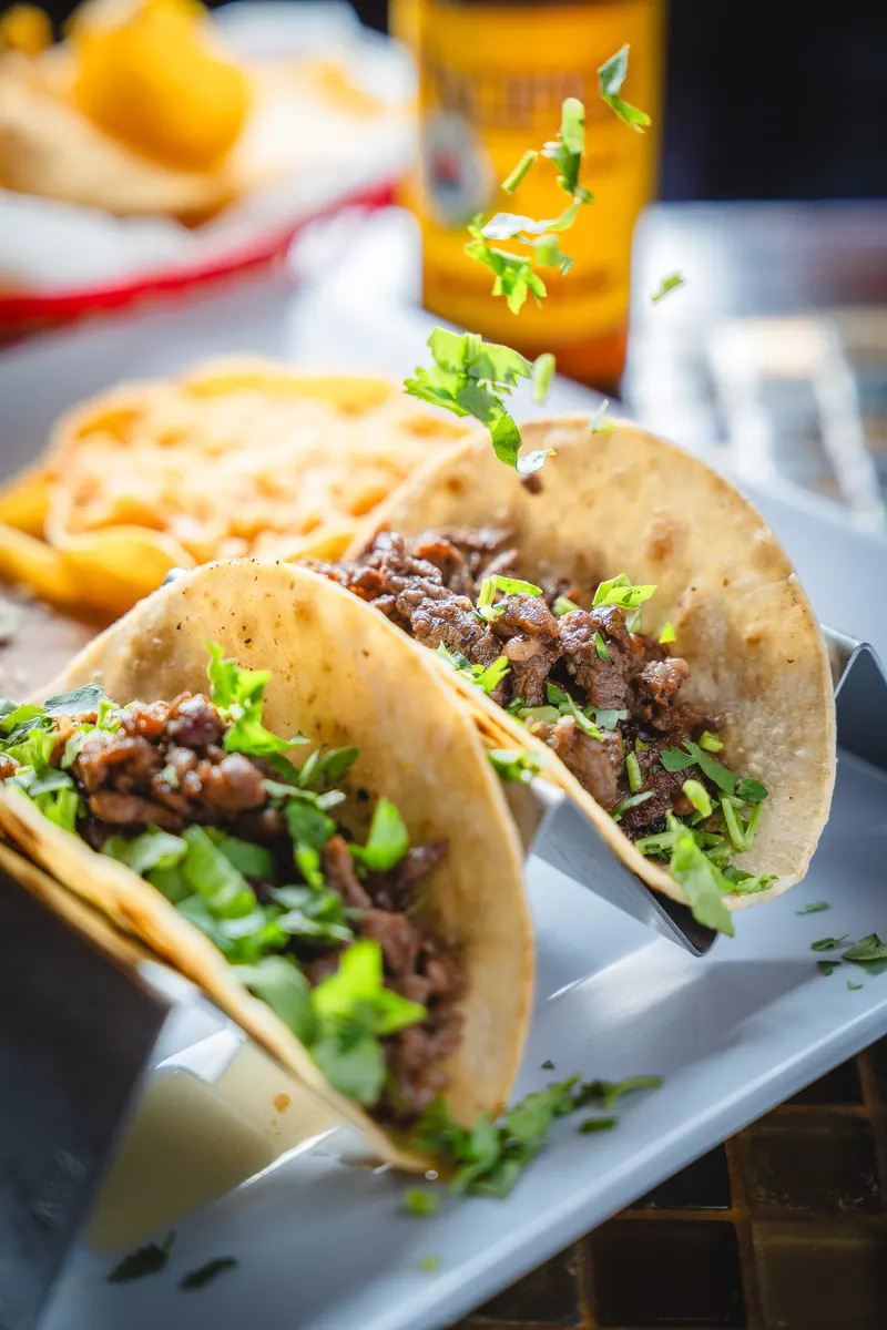 Tacos topped with cilantro on a white platter